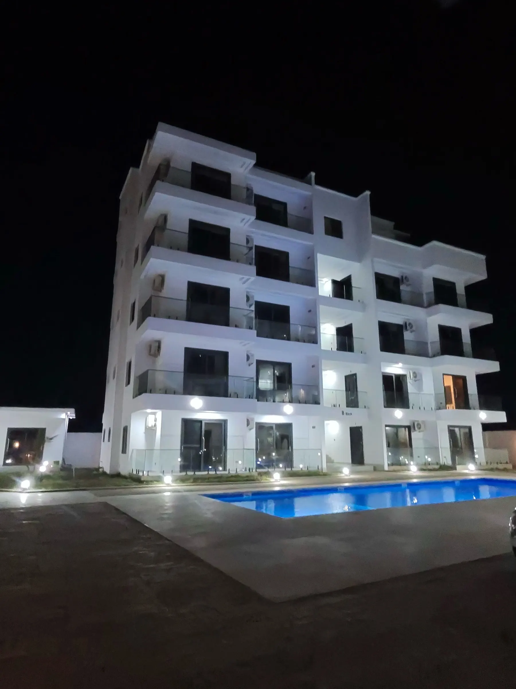 Apartment block lit at night above the pool